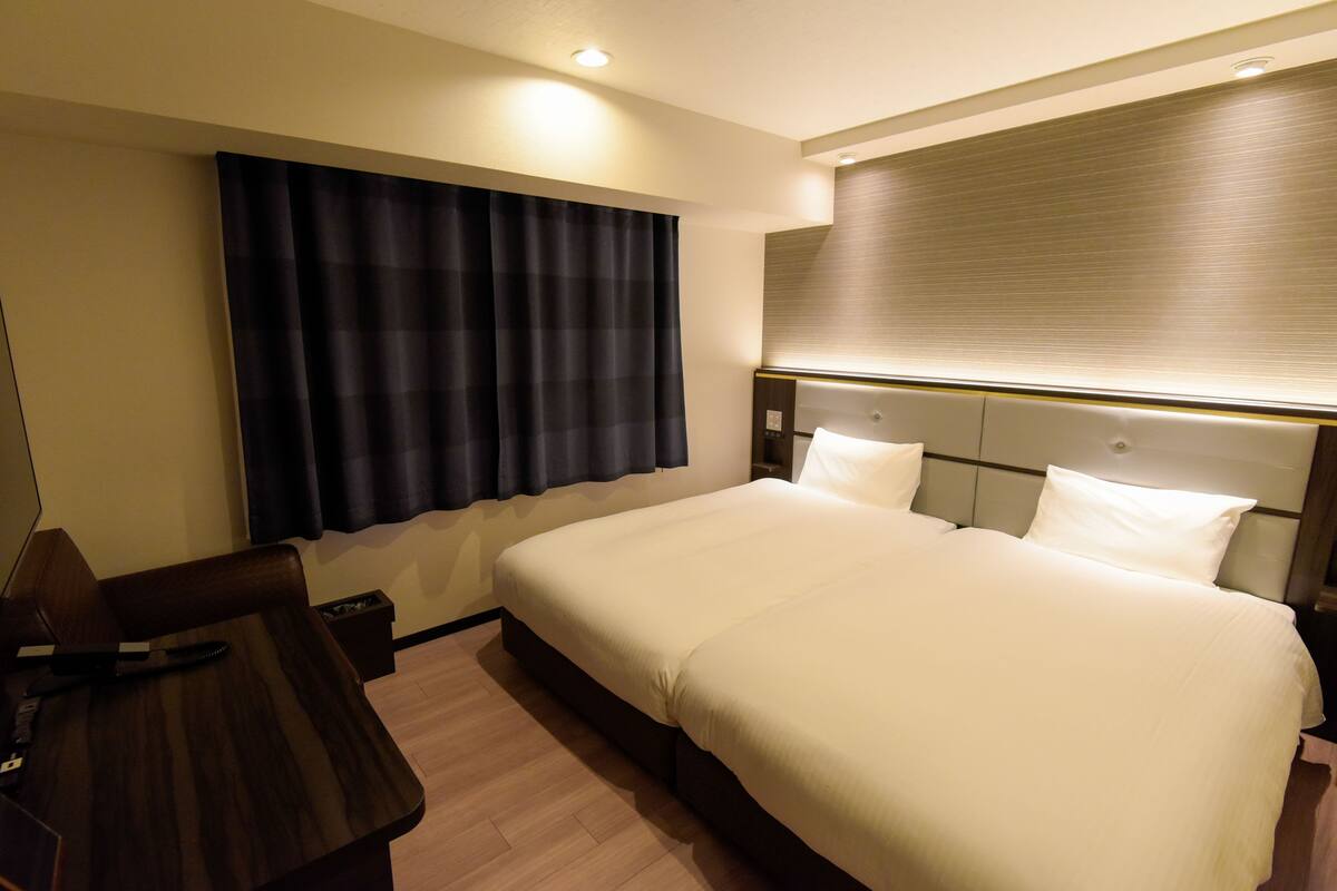 A hotel room with a large bed, a desk, and a chair.