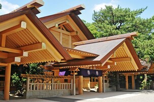 Un edificio japonés tradicional con techo inclinado, vigas de madera y base de piedra.
