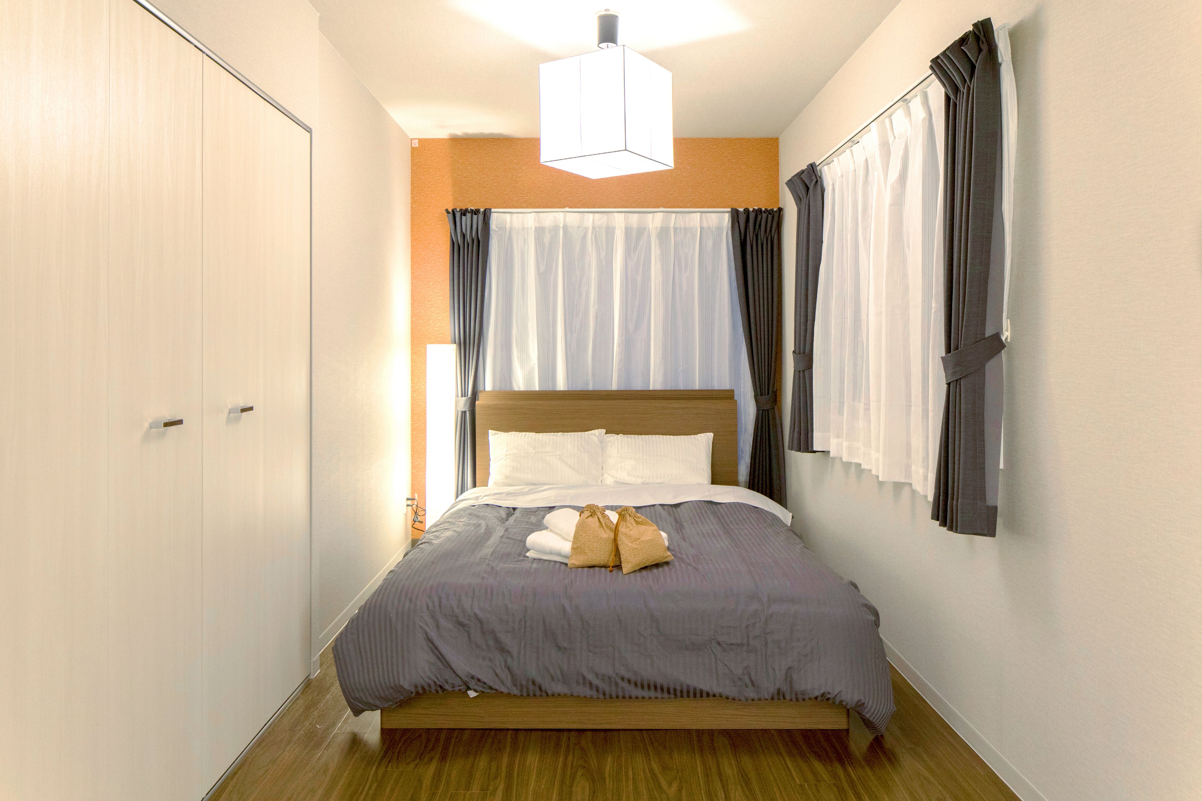 Una cama bien hecha con cabecera de madera, una mesita de noche y una lámpara colgante.