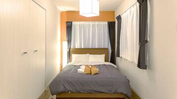 Una cama bien hecha con cabecera de madera, una mesita de noche y una lámpara colgante.