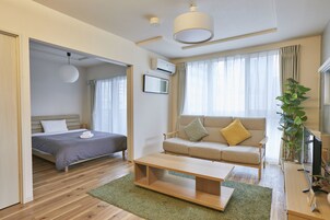 Una habitación de hotel moderna con una cama, un sofá, una mesa de centro y un televisor.