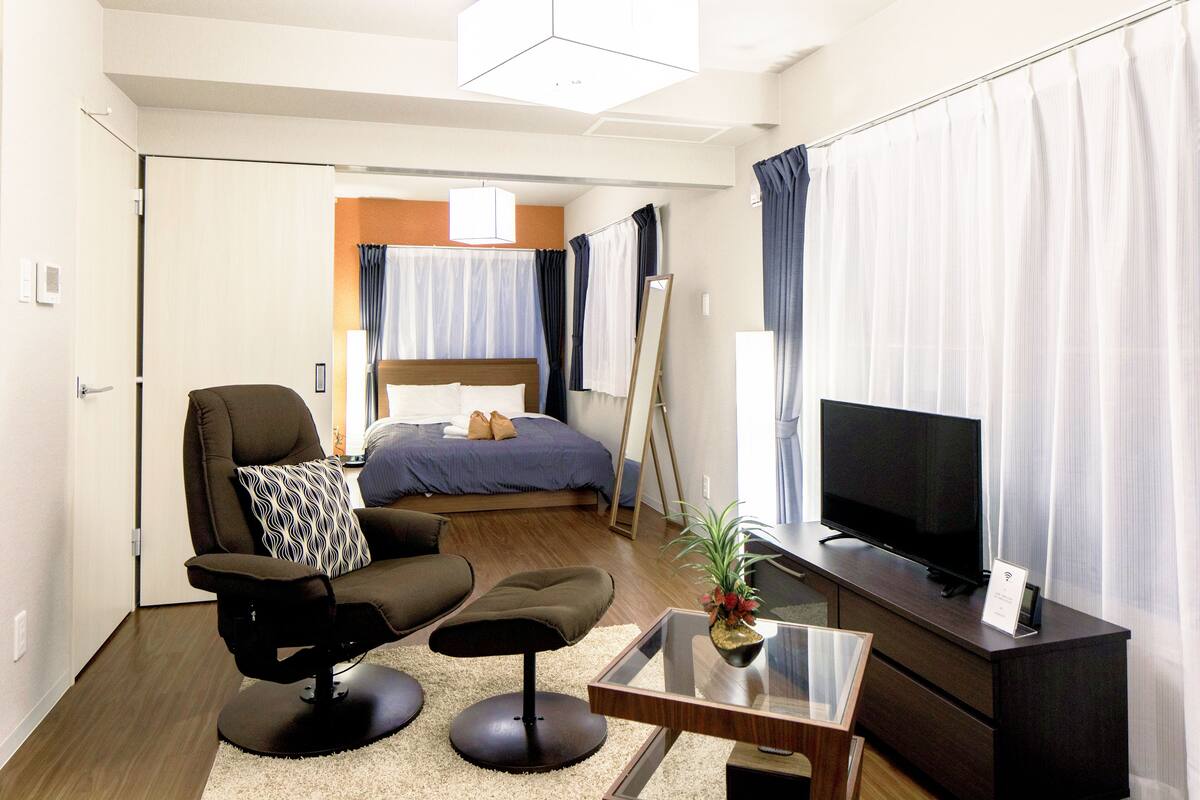 Una habitación de hotel con cama, televisor, escritorio, silla y sofá.