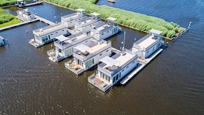 A floating complex with multiple interconnected buildings, docked boats, and a narrow waterway.