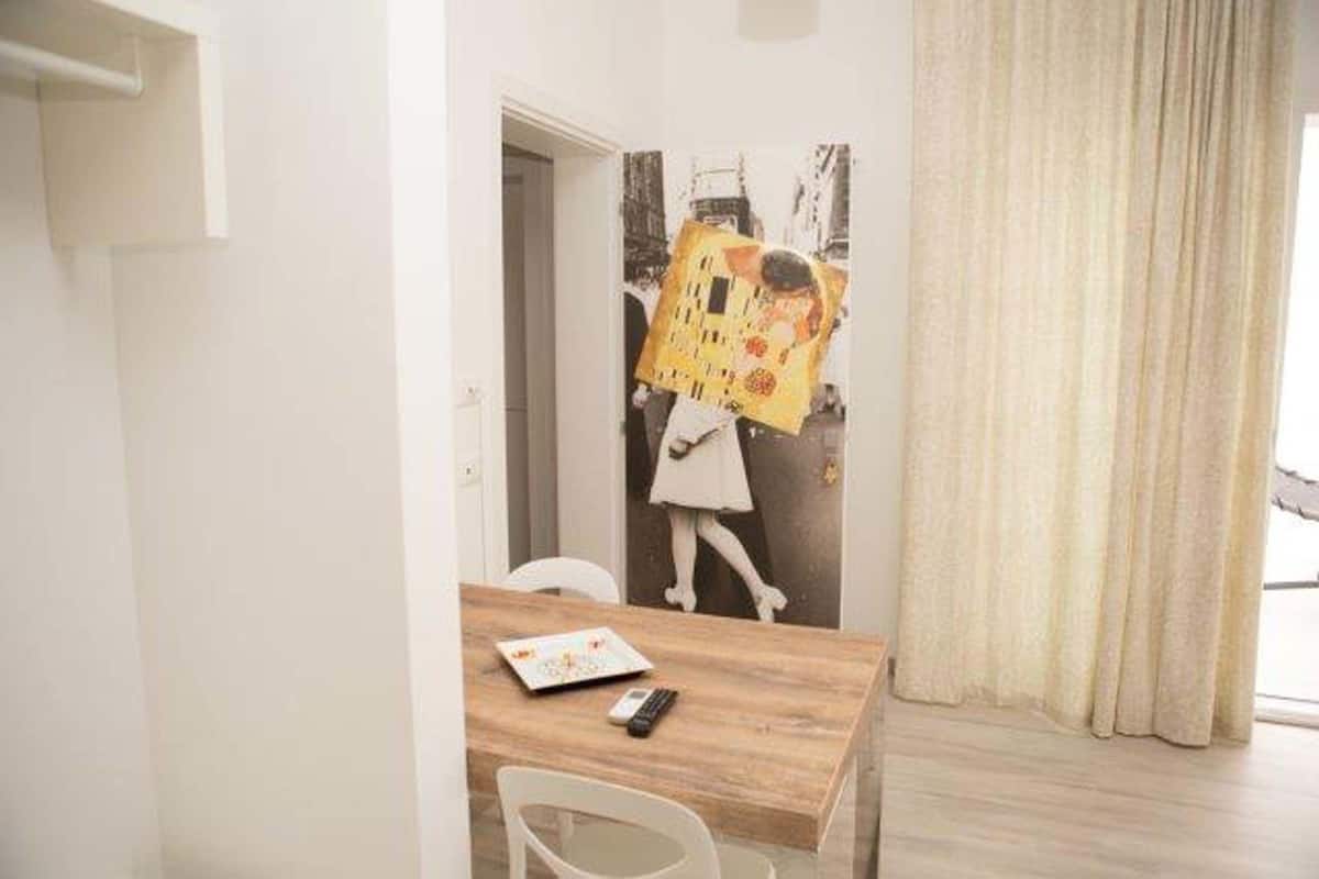 Una habitación con una mesa de madera, una silla blanca y una puerta que da a otra estancia.