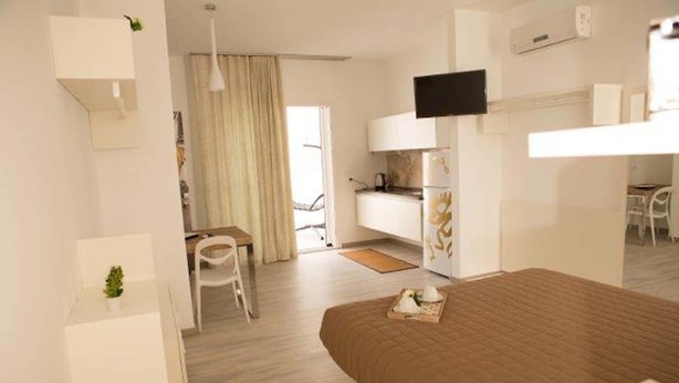 Una habitación de hotel moderna con cama, escritorio, silla, televisor y kitchenette.