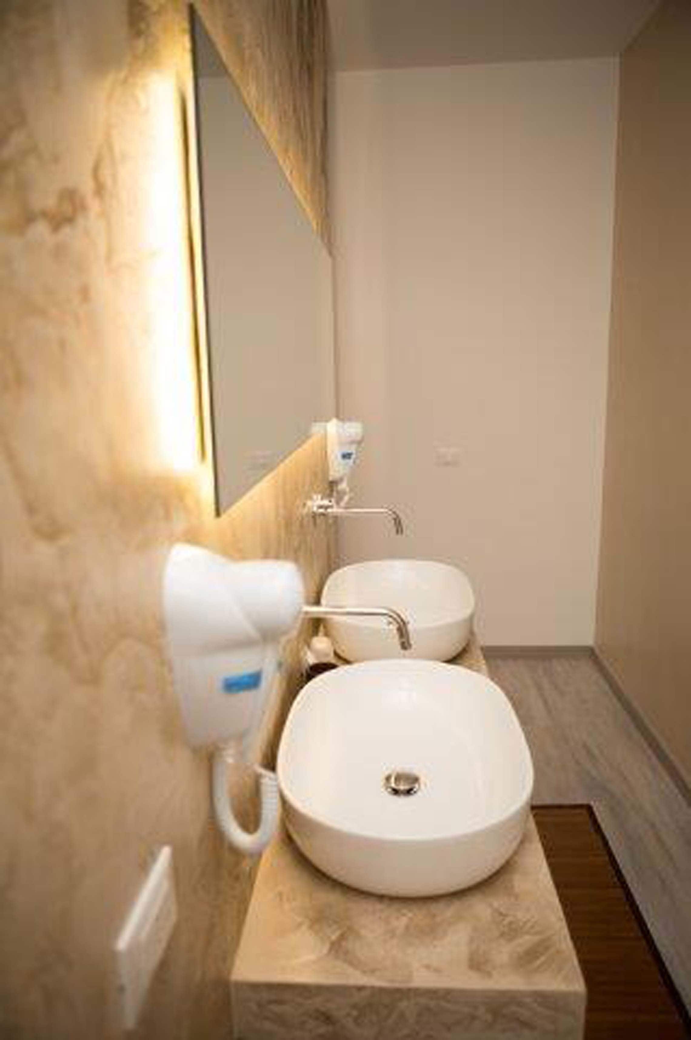 Un baño moderno con dos lavamanos, un secador de pelo y un espejo.