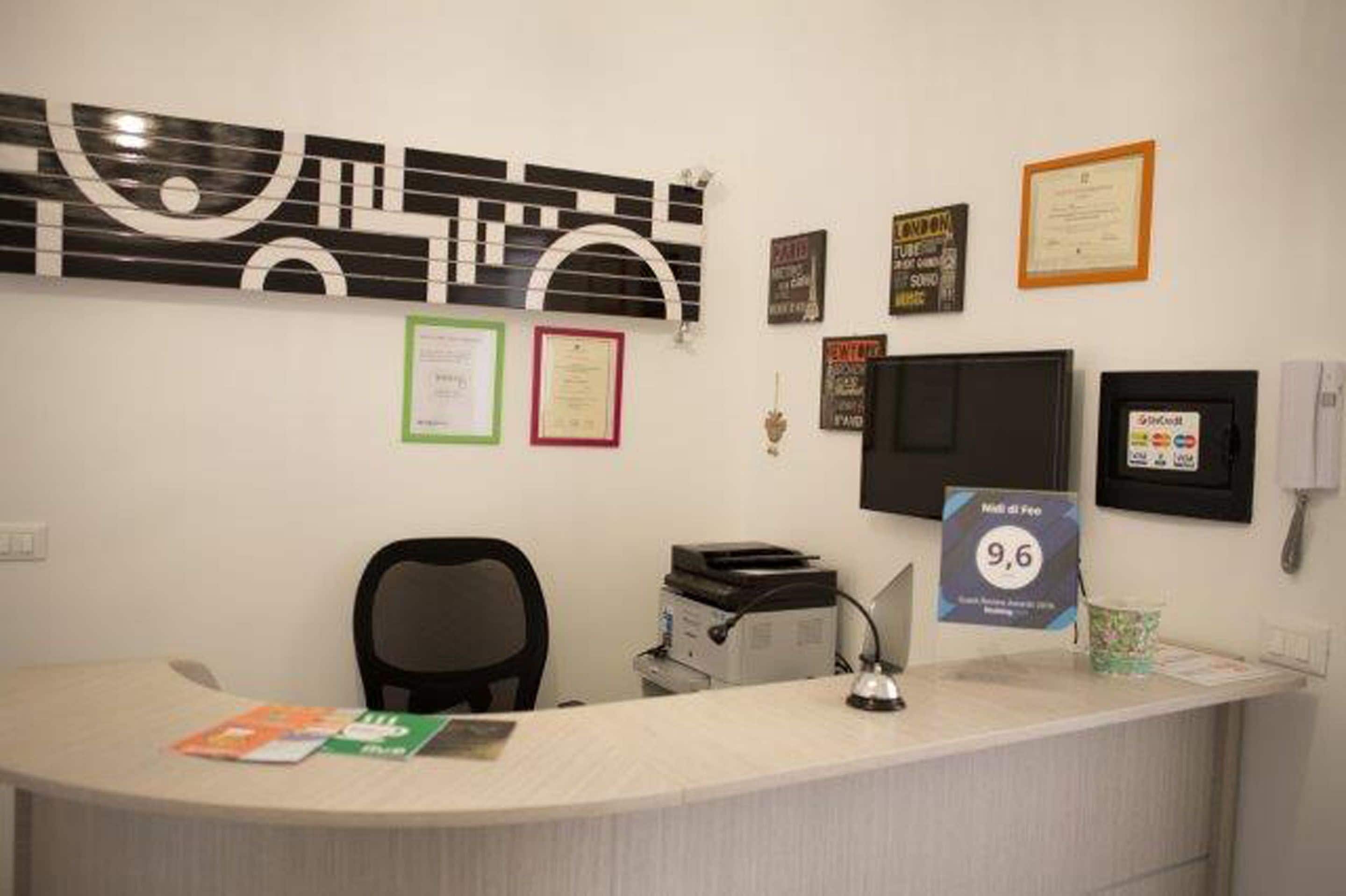 A reception desk with a computer, printer, and framed certificates on the wall.