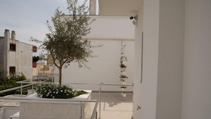 Un edificio moderno con fachada blanca, un pequeño árbol y una jardinera.
