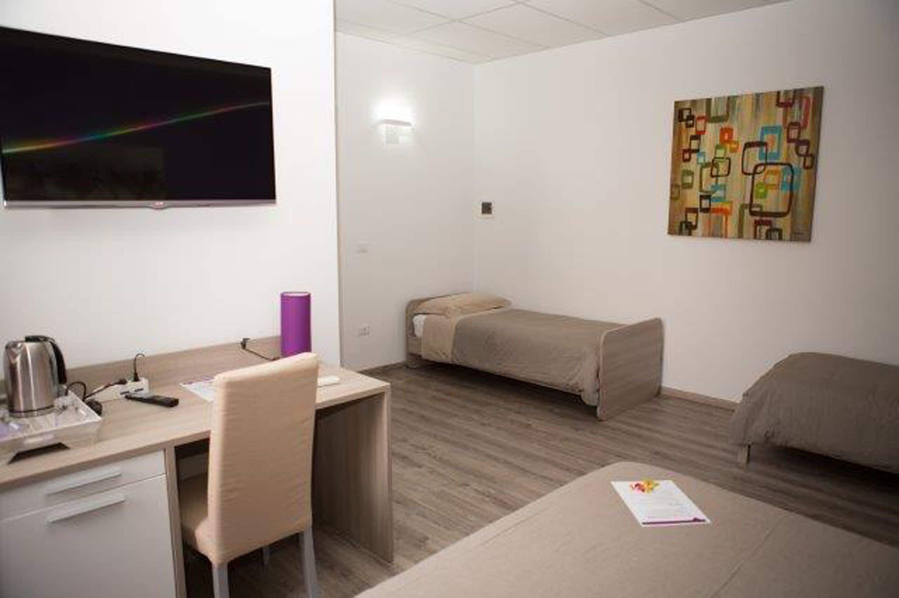 Ein Hotelzimmer mit Schreibtisch, Stuhl, Bett und einem Kunstwerk an der Wand.