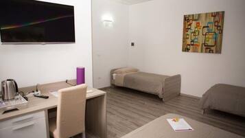 Ein Hotelzimmer mit Schreibtisch, Stuhl, Bett und einem Kunstwerk an der Wand.