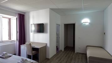 Une chambre d’hôtel avec un lit, un bureau, une chaise, une télévision et une porte de salle de bain.