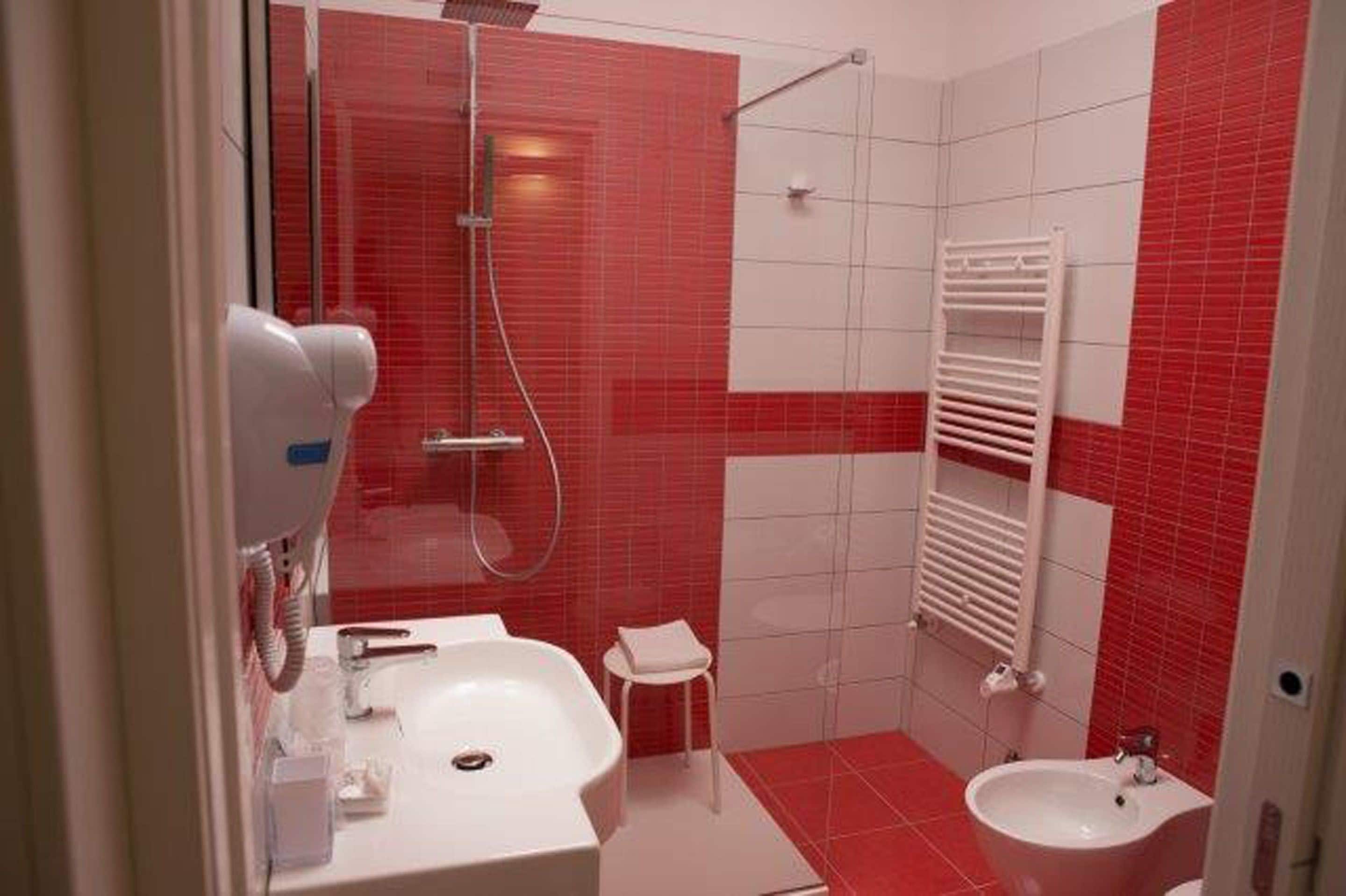 Un baño con ducha, dos lavamanos y un perchero para toallas.