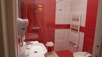Un baño con ducha, dos lavamanos y un perchero para toallas.