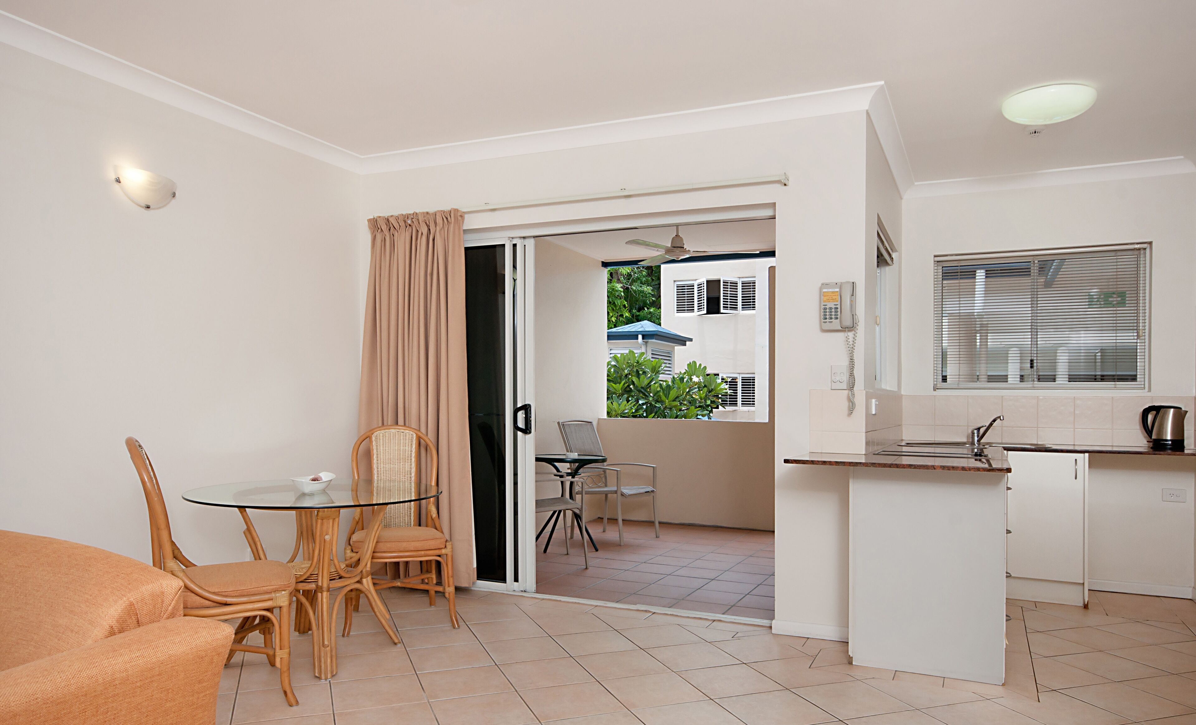 A compact living space with a dining area, kitchenette, and a sliding door leading to an outdoor area.