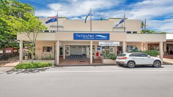 A hotel named "The NewPort On Macrossan" with a signboard, a car parked in front, and flags on the roof.