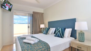 Ein Hotelzimmer mit einem Bett, zwei Nachttischen, einem Fernseher und Blick ins Freie.