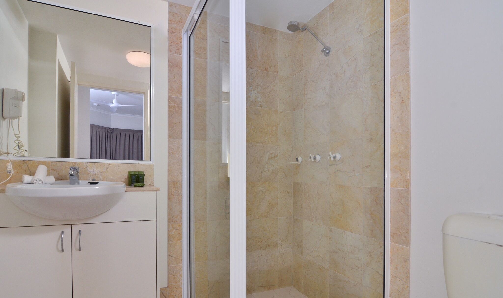 Baño con lavamanos, espejo y ducha.