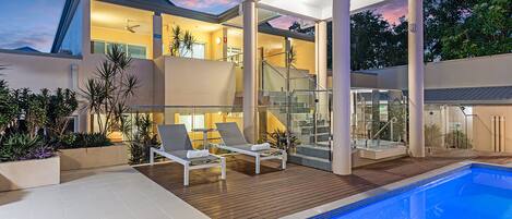A modern house with a swimming pool, outdoor seating, and a covered patio area.