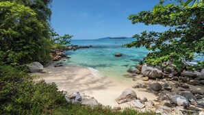 A beach with clear water, rocks, and greenery. - Villa Analaya (Kamala)