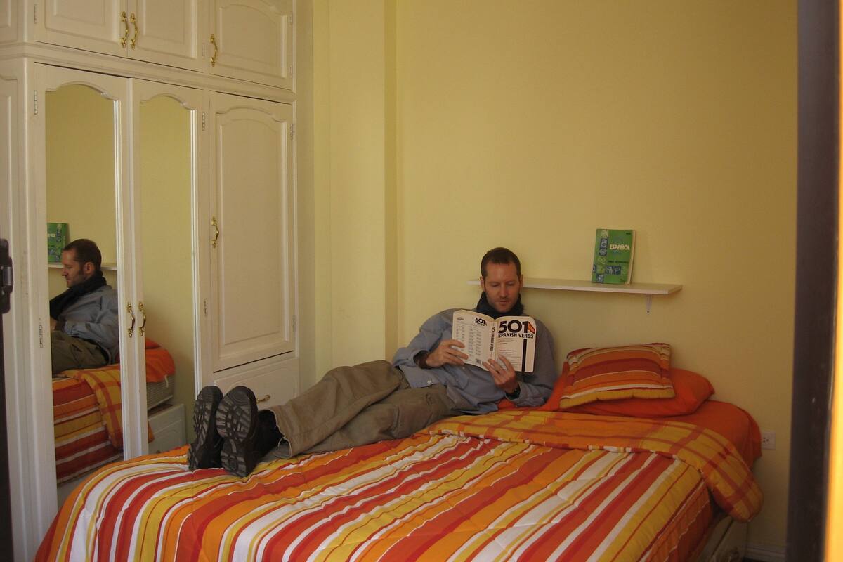 Een slaapkamer met twee bedden, een kledingkast en een plank met een boek.