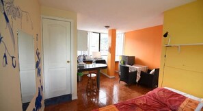 A compact room with a bed, a small dining table, a kitchenette, and a window. - Mayra's Spanish School (Baños de Agua Santa)