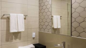 Un baño moderno con un espejo grande, un lavamanos blanco y un perchero para toallas.