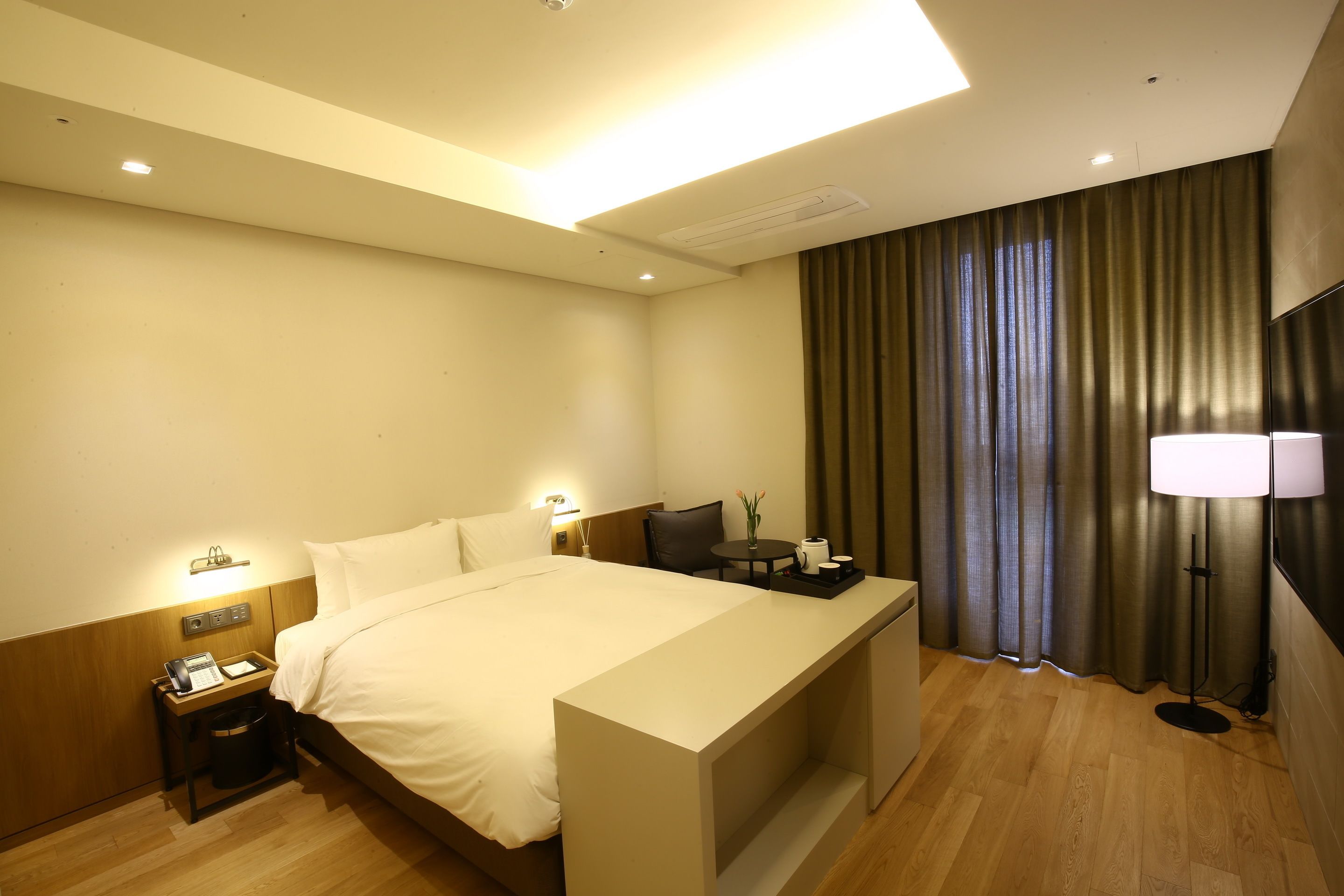 Une chambre d’hôtel avec un lit, une table de chevet, une lampe et des rideaux.