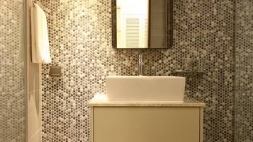 A bathroom with a white sink, a mirror, and a tiled wall with a circular pattern.