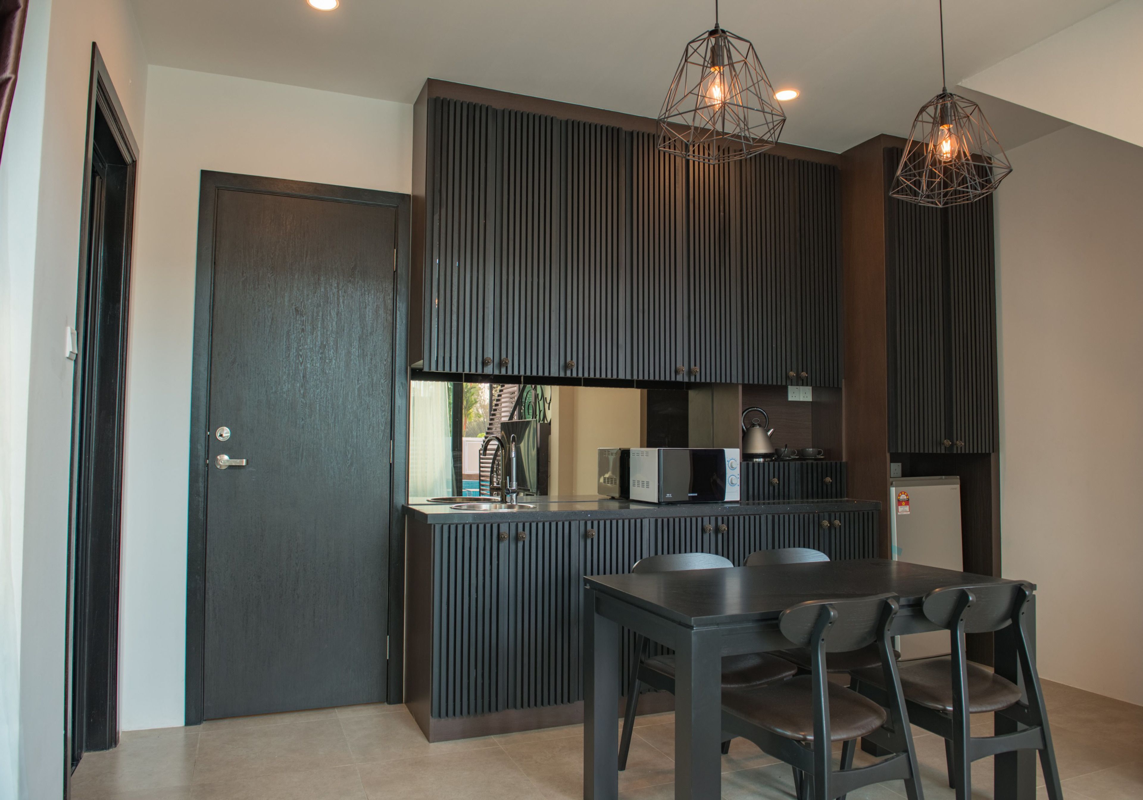 Una cocina moderna con armarios oscuros, una isla central e iluminación colgante.