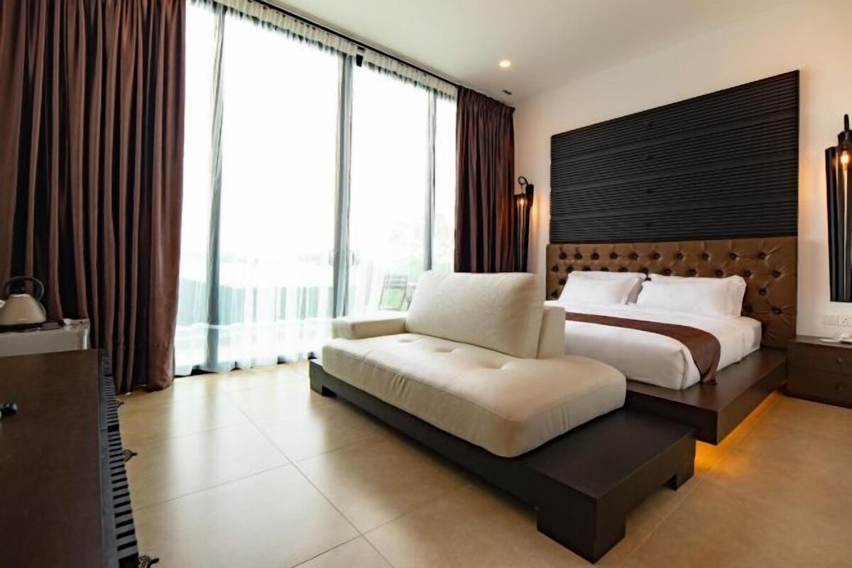A modern hotel room with a large bed, a sofa, and a view of the city.