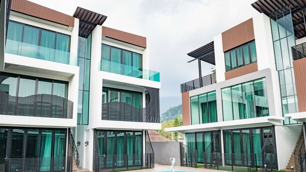 Un hotel moderno con piscina central, varios balcones y ventanas amplias.