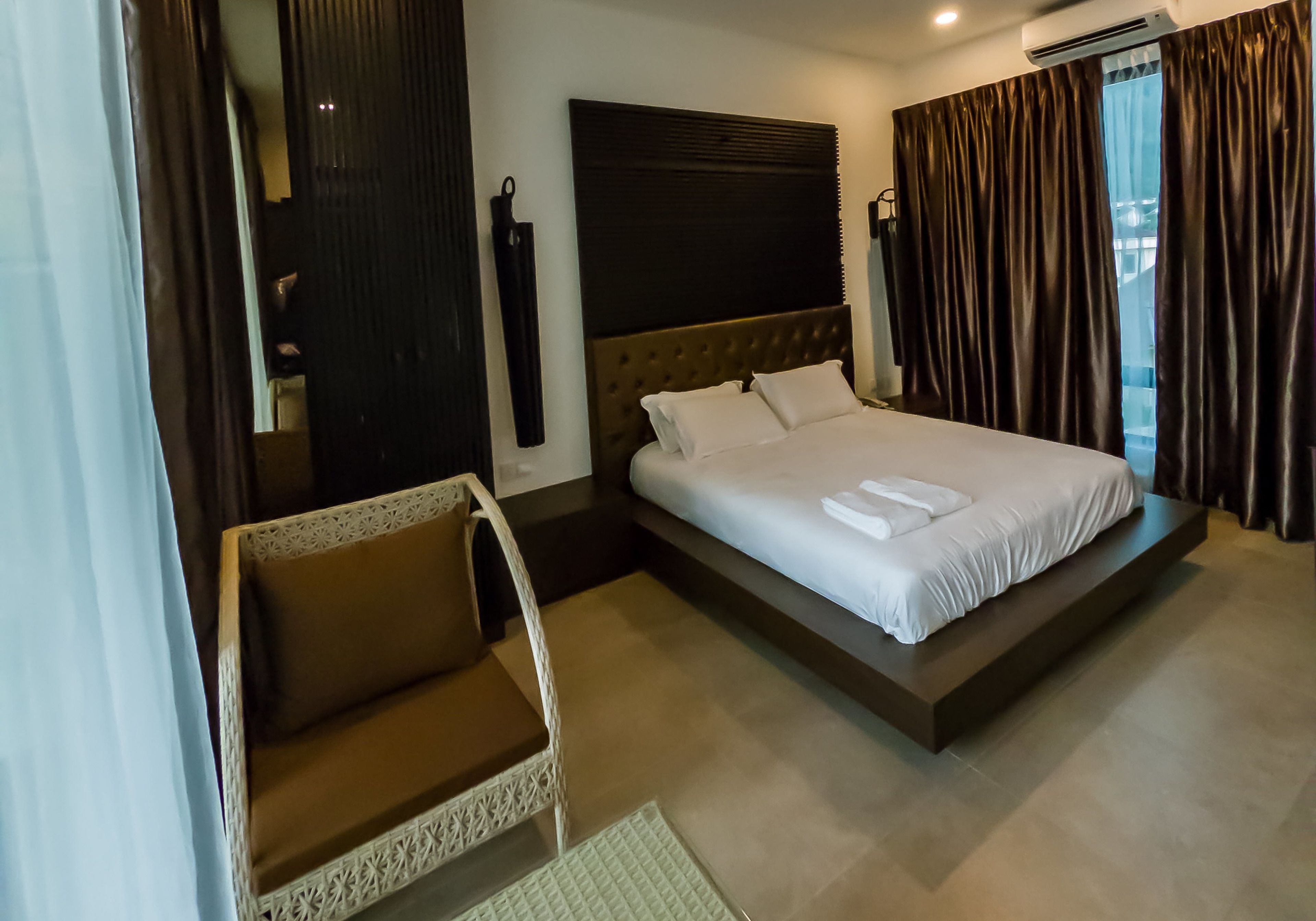 A modern hotel room with a large bed, a sitting area, and a view of the city.