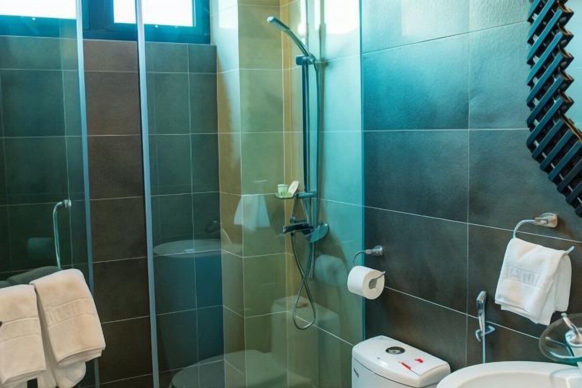 Un baño moderno con ducha separada por mampara de vidrio, inodoro y lavamanos.