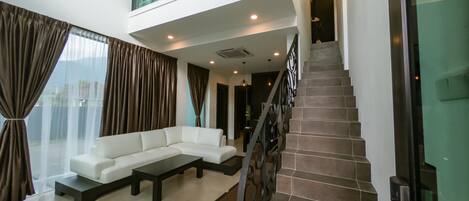 A modern living room with a white sectional sofa, a coffee table, and a staircase with a metal railing.