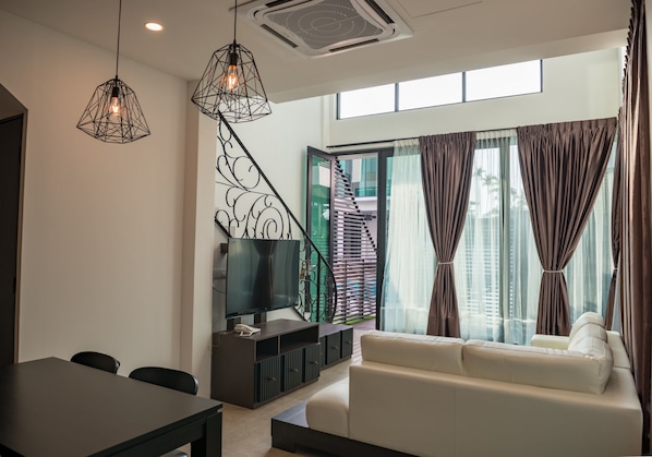 A modern living room with a sofa, a TV, and a dining area with chairs and a table. - Hermitage Boutique House (Taiping)