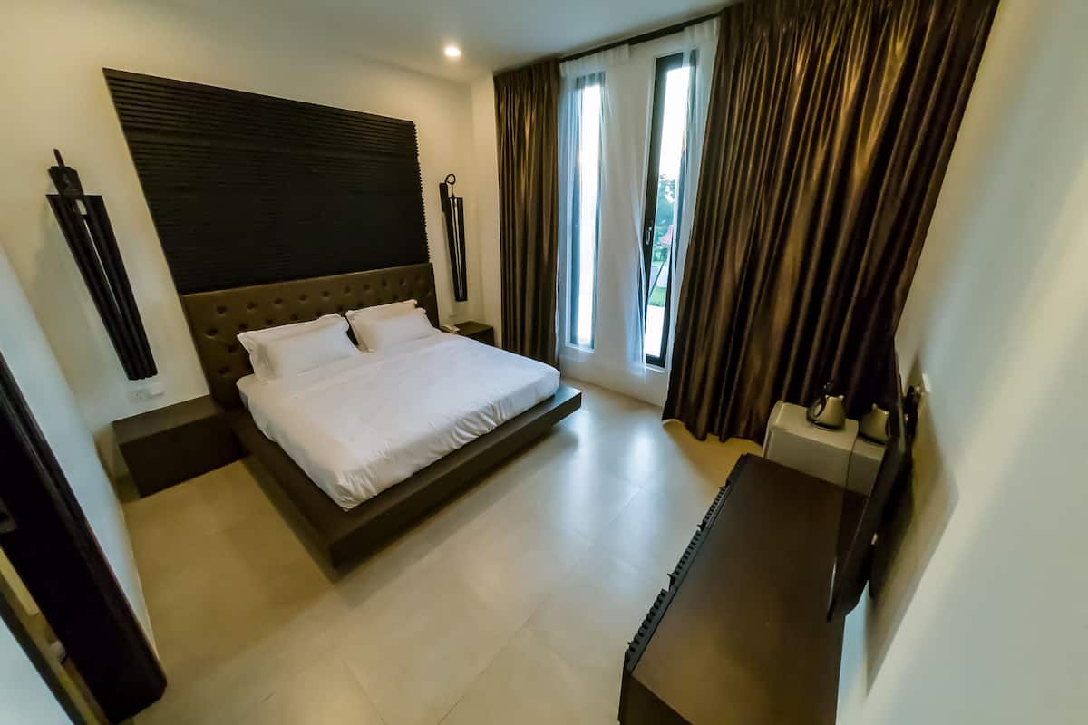 Een moderne hotelkamer met een groot bed, een flatscreen televisie en uitzicht op het omliggende landschap.