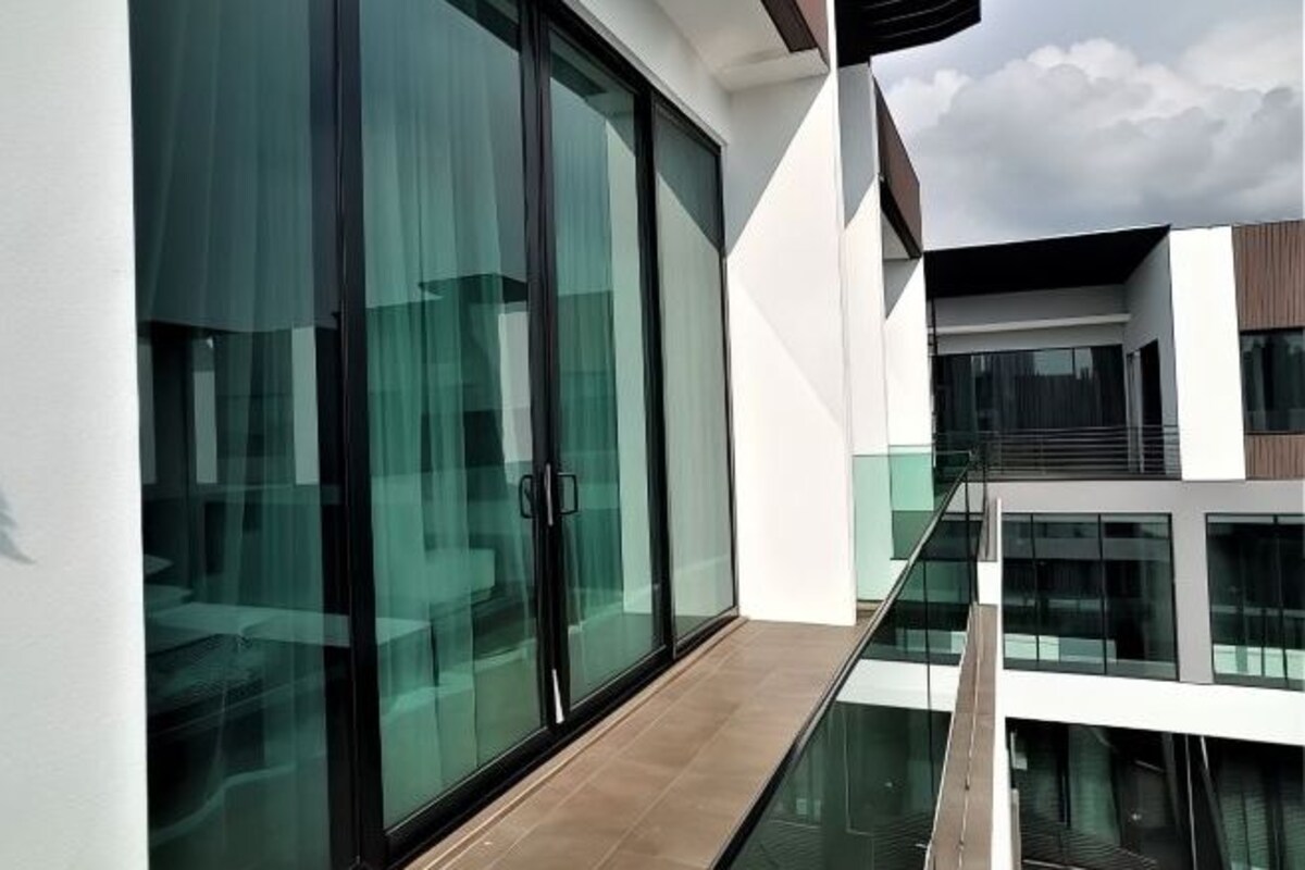 Ein modernes Gebäude mit großen Glasfenstern und einem Balkon mit Glastrennwand.