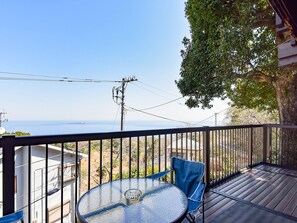En balkon med et bord og stole, der giver udsigt over et smukt hav- og landskab.