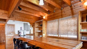 Ein Holzinterieur mit Barbereich, Barhocker und einer Küche im Hintergrund.