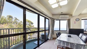 Ein Zimmer mit einem großen Balkon, einem Esstisch mit Stühlen und Blick ins Freie.