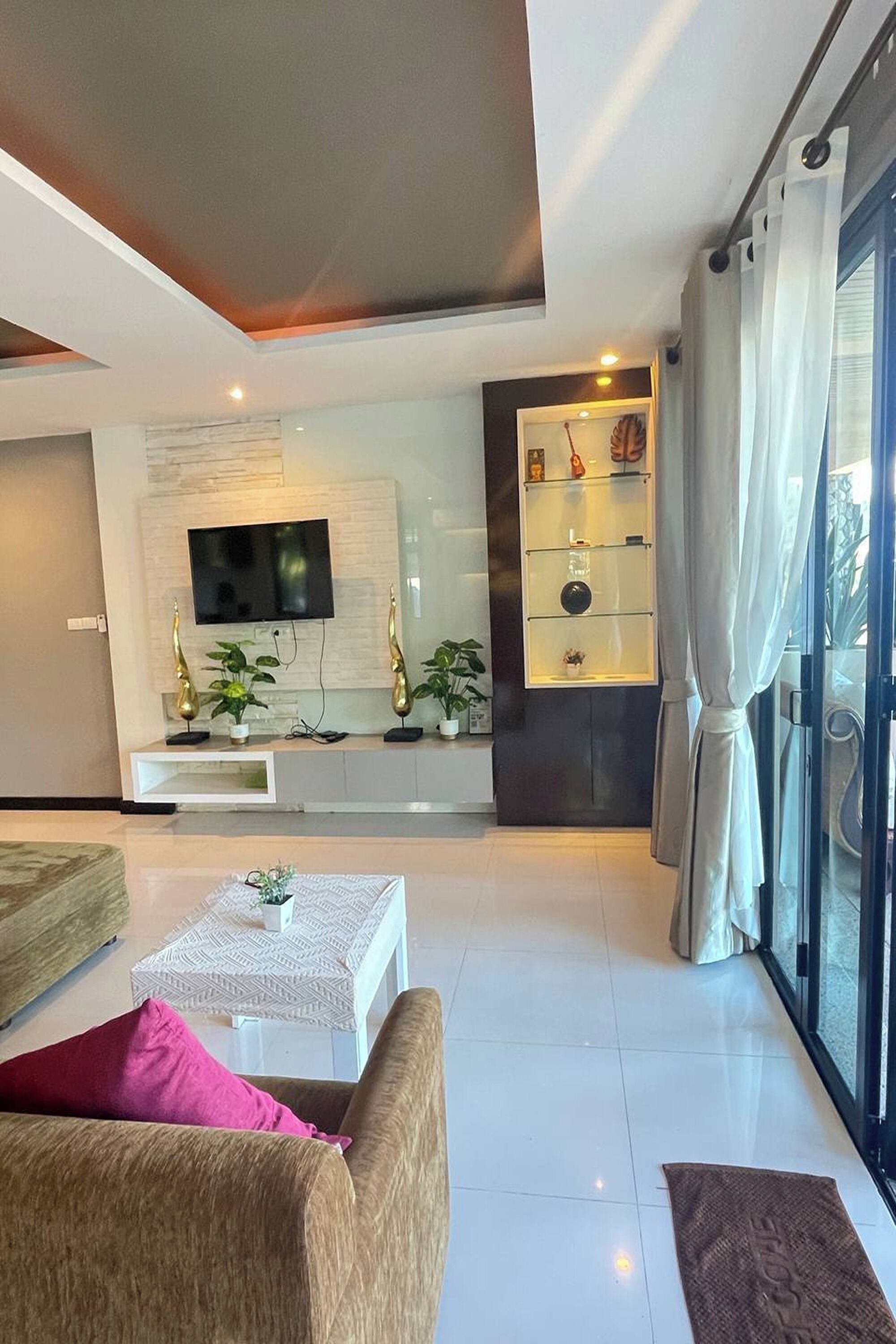 A modern living room with a flat-screen TV, a glass display cabinet, and a sofa.