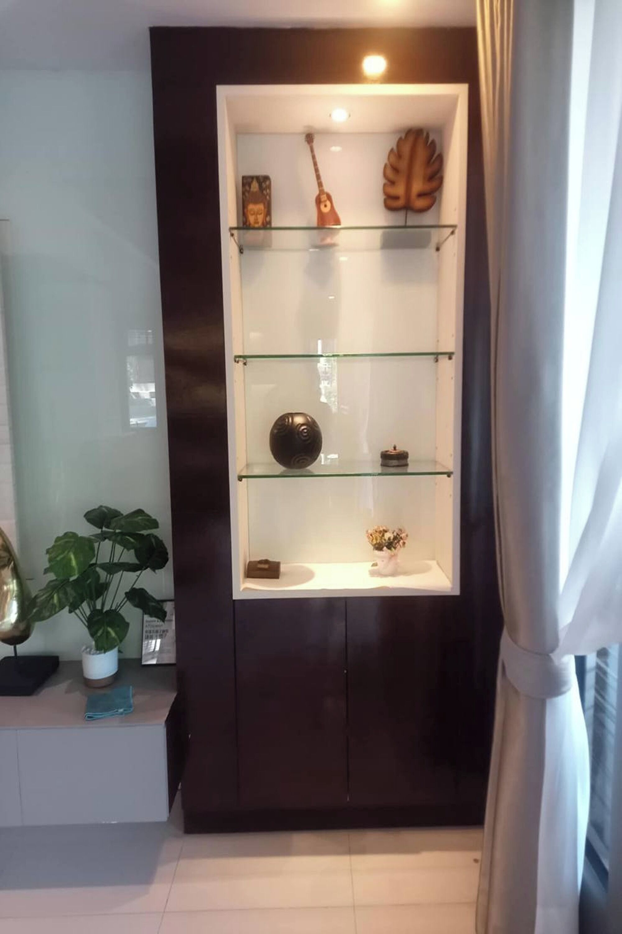 A modern room with a dark wall and a glass shelving unit displaying decorative items.
