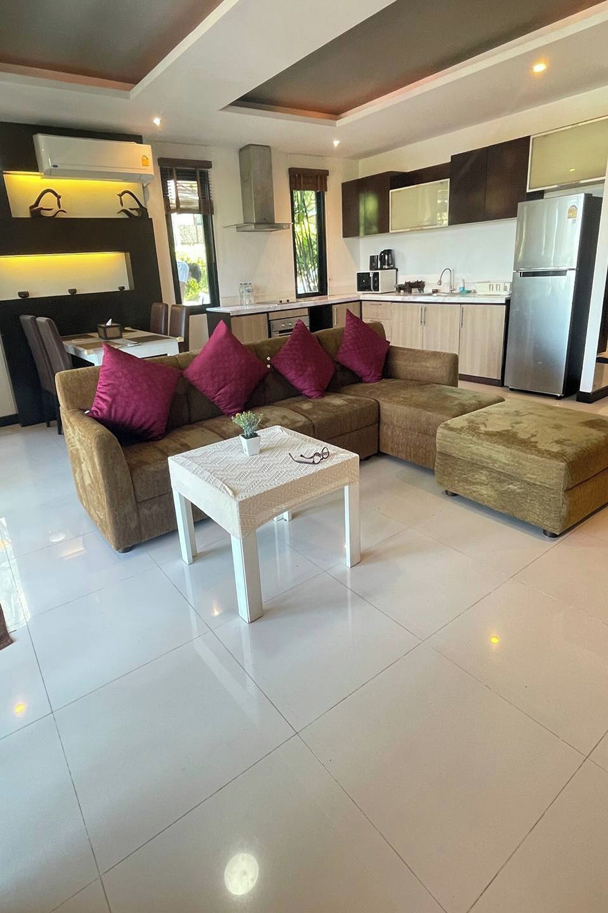 A modern living room with a sectional sofa, a white coffee table, and a kitchen area in the background.