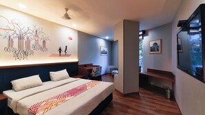 A modern hotel room with a large bed, a wall mural, a seating area, and a TV. - Ginger Vadodara RCR (Vadodara)