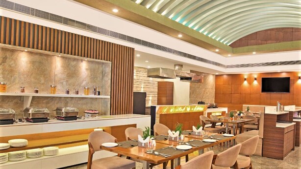 A modern restaurant with a central dining area, a buffet with various food items, and a kitchen area. - Ginger Vadodara RCR (Vadodara)
