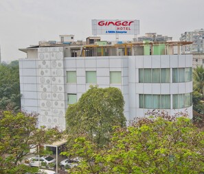 Un edificio con un cartel de Ginger Hotel, que presenta un diseño moderno con patrones geométricos en la fachada y numerosas ventanas.