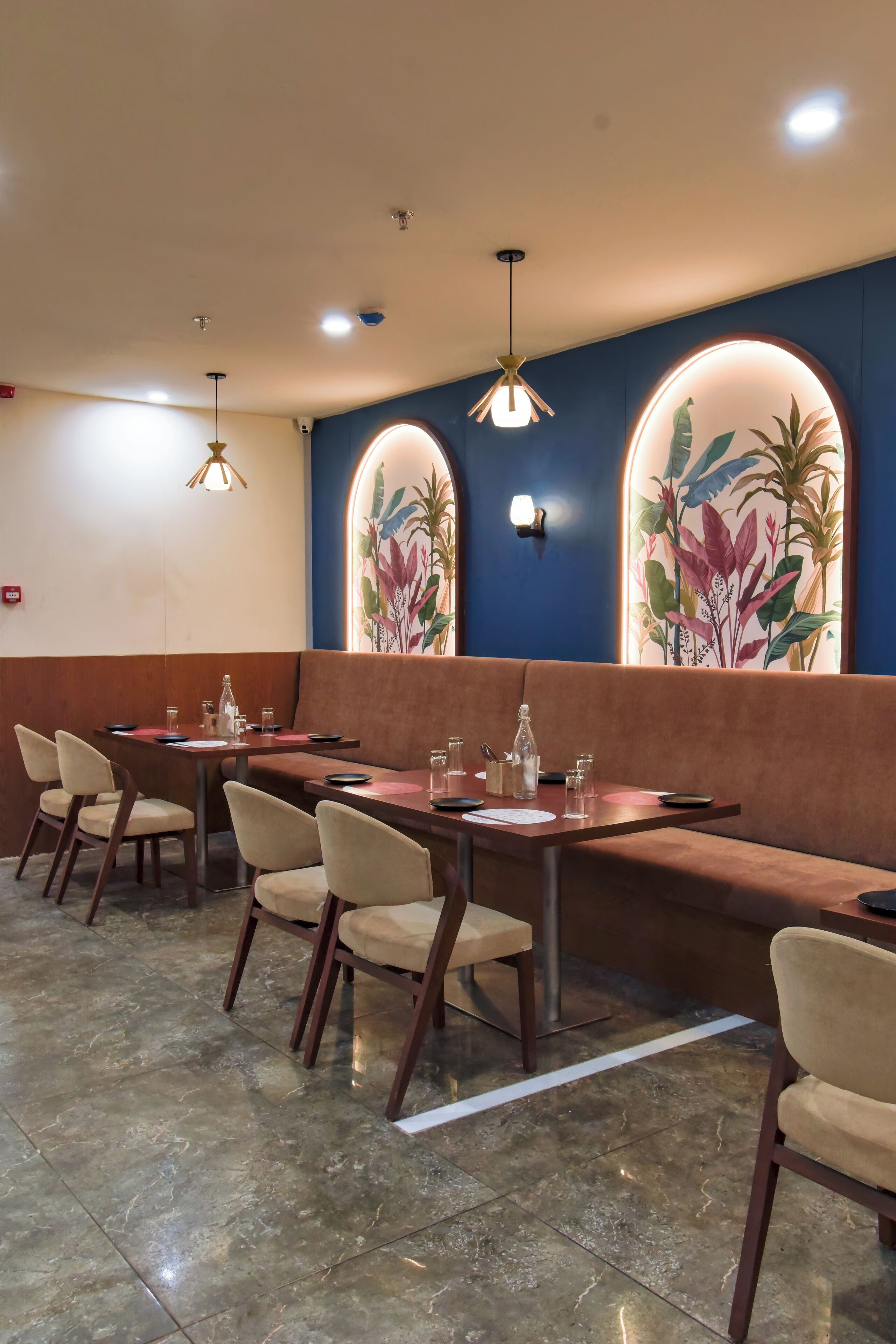 Ein Restaurant mit Sitzgelegenheiten, Tischen, einem Fliesenboden und Wandbildern.