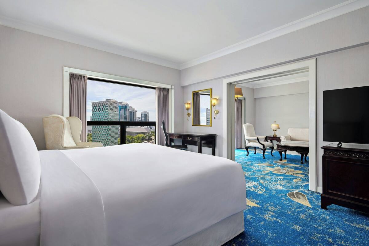 A hotel room with a large bed, a desk, a TV, and a view of the cityscape.