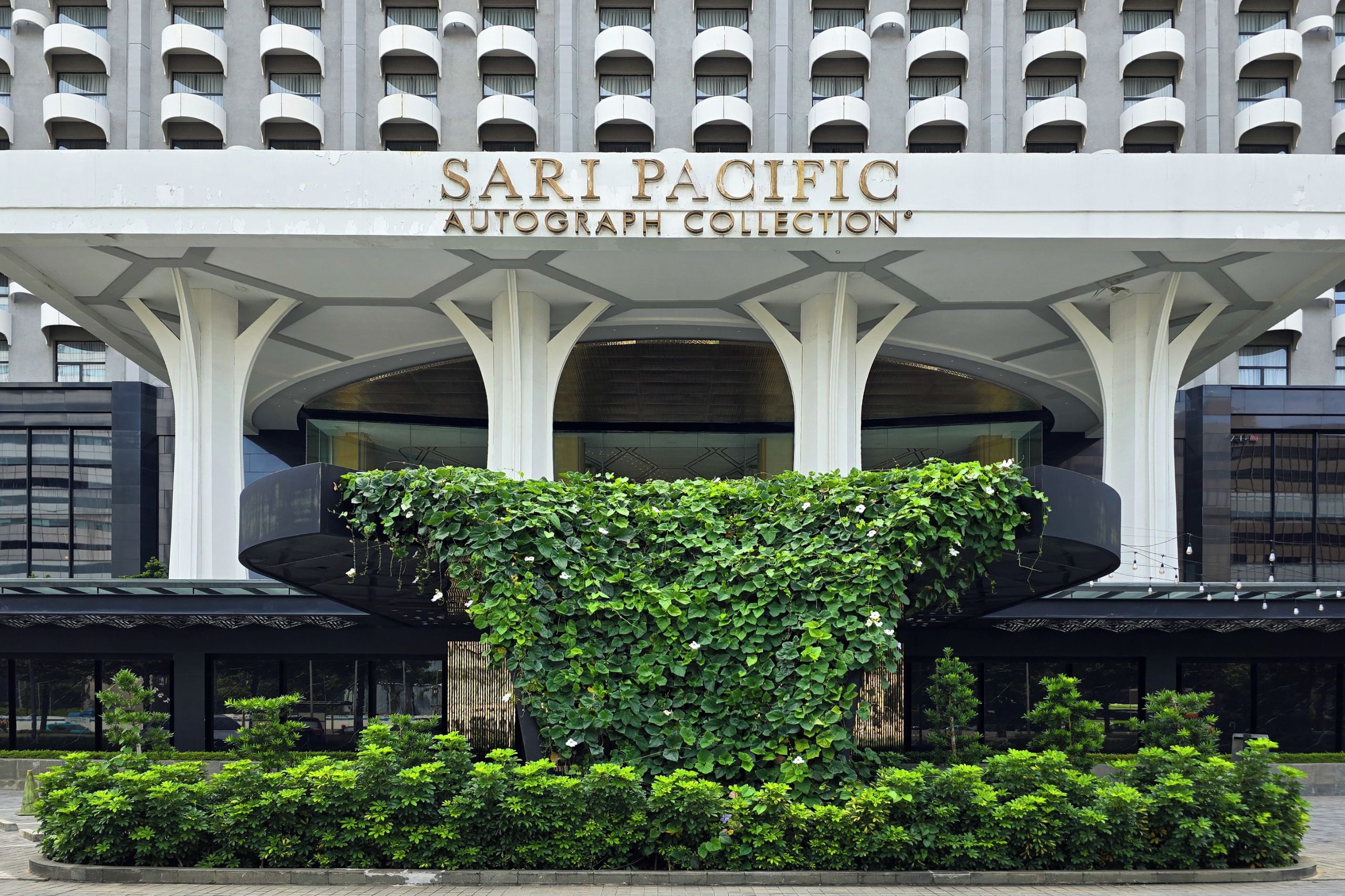 Un edificio con un letrero que dice 'SARI PACIFIC AUTOGRAPH COLLECTION' sobre una entrada cubierta.
