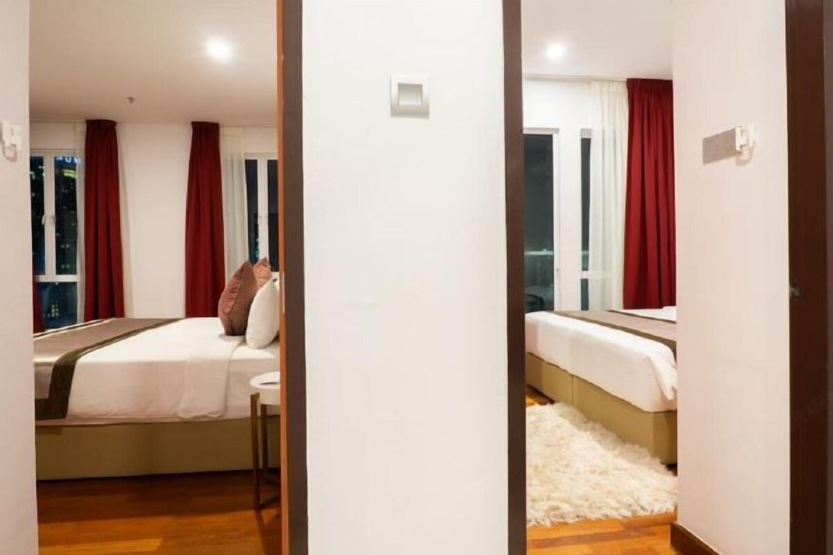 Ett hotellrum med en säng, ett litet bord och ett fönster med röda gardiner.